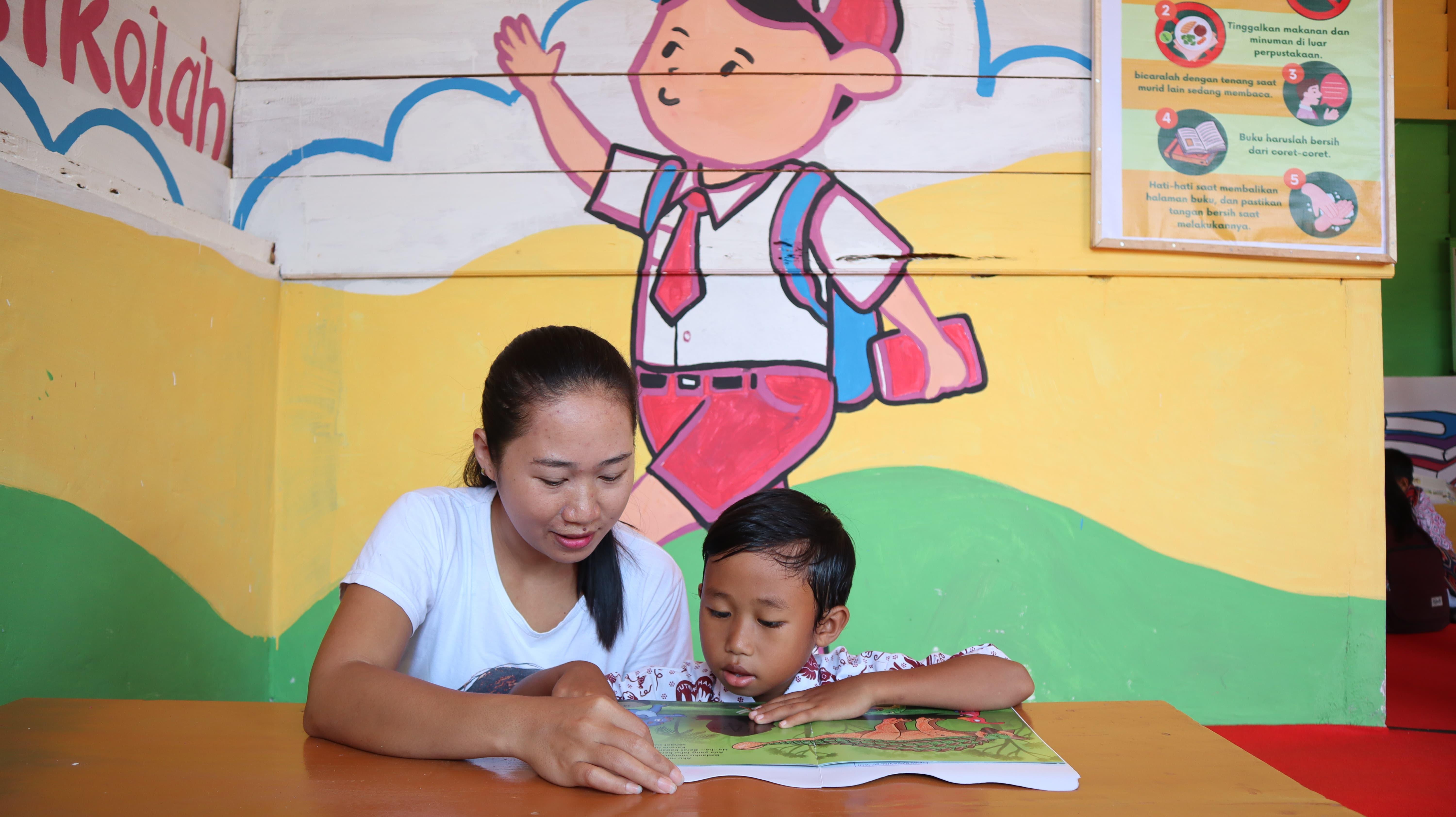 a teacher reading a book with her student in Indonesia