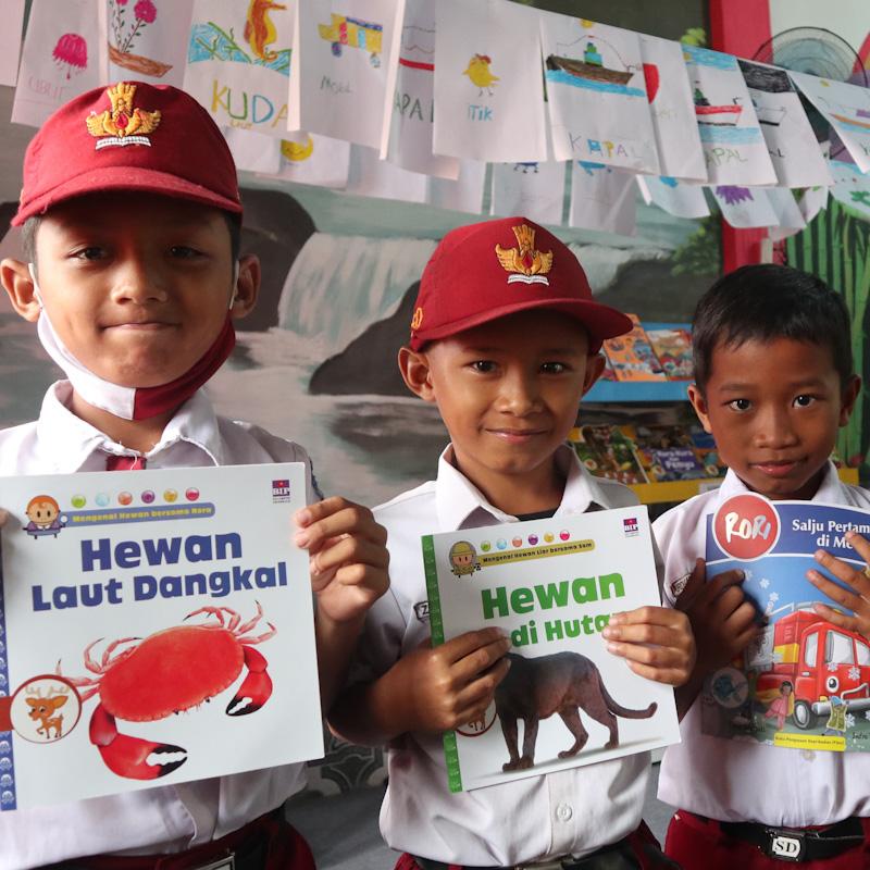 3 school boys showing their books